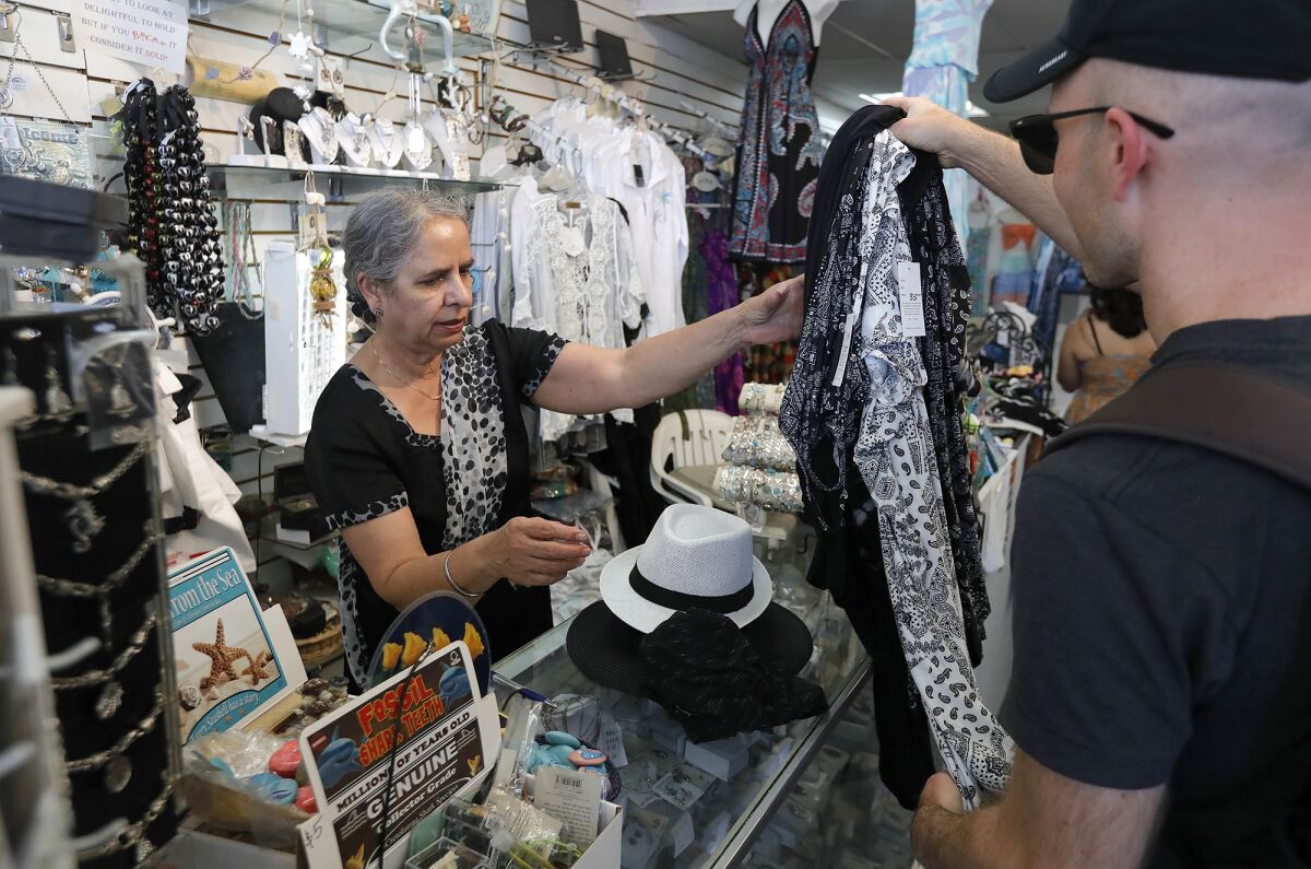 Ranjit Mac, owner of Blue Sails gift shop, checks out a customer Thursday, April 7, 2022.
