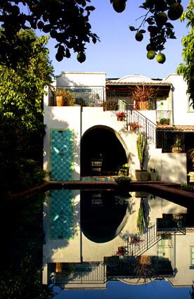 Whitney Greens garden in Santa Monica, designed by Stephen Gabor of Gabor + Allen Inc., is made up of a series of colorful and playful vignettes that artfully mix low-water cactuses and succulents with fruit trees, roses and other blooming plants. Lemons drip over the backyard swimming pool, which reflects the patios and the outdoor showers blue tile. Under the arch is a shaded living room. The staircase to the terrace is dotted with potted plants.