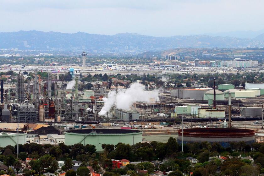 FILE - This May 25, 2017 aerial photo shows the Standard Oil Refinery in El Segundo, Calif., with Los Angeles International Airport in the background and the El Porto neighborhood of Manhattan Beach, Calif., in the foreground. A plan to extend California's cap-and-trade program for another decade looks beyond cutting greenhouse gas emissions and takes aim at toxic air in the polluted neighborhoods around refineries and factories. (AP Photo/Reed Saxon, File)