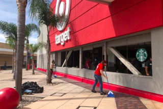 Workers clean up broken glass on Sunday at the Target store at Grossmont Center in La Mesa.