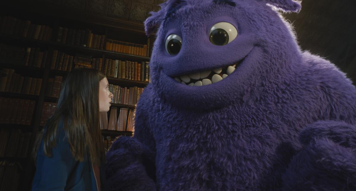 A girl speaks with a large purple creature.