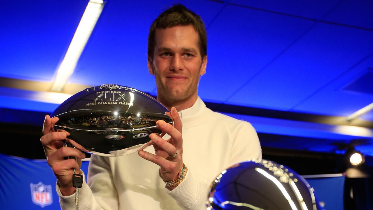 New England Patriots quarterback Tom Brady holds his Super Bowl XLIX MVP award during a news conference Feb. 2, the day after the game.