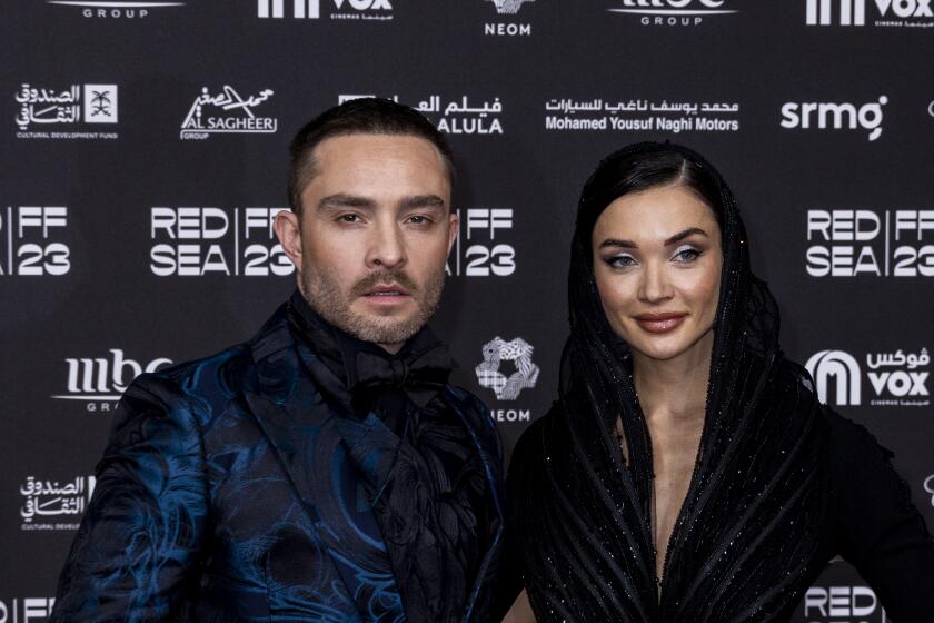 Ed Westwick and Amy Jackson dressed in dark formalwear pose together for a photo at a film festival