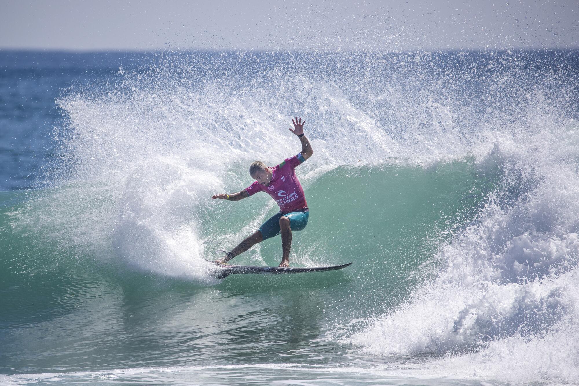 Filipe Toledo does a turn on a big wave while competing against Gabriel Medina