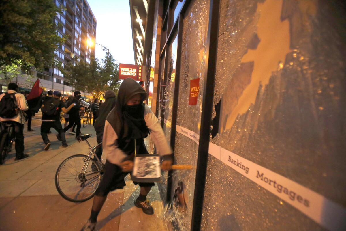 Demonstrators with their faces covered break windows at a Wells Fargo bank during one of the May Day protests in Oakland on Friday.