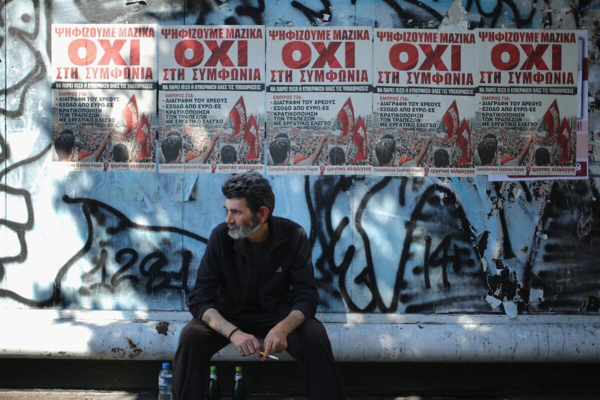 A man sits on a bench in front of campaign posters urging voters to vote no in a July 5 referendum on whether to accept terms from Greece's major lenders for another bailout.