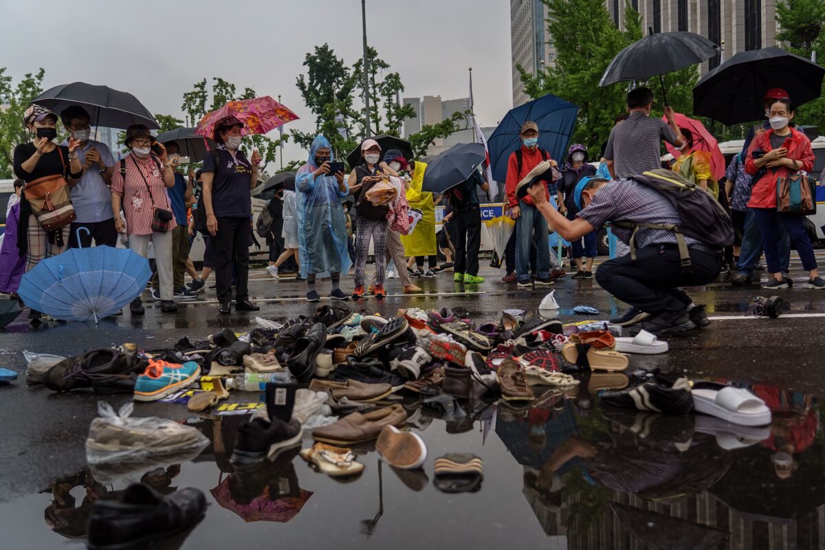 Protesters throw shoes at a pile of old shoes to signal their dissatisfaction at the government, in Seoul.