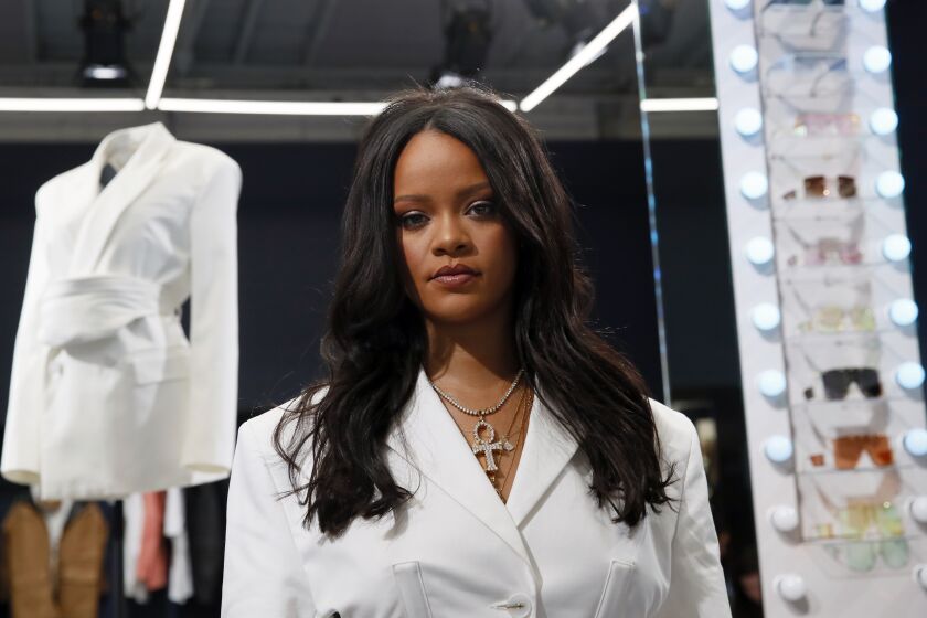 Rihanna posing in a white suit and cross necklace