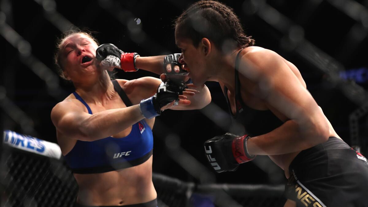 Amanda Nunes lands an overhand right to an already battered face of Ronda Rousey during their bantamweight title fight Friday. To see more images from UFC 207, click on the photo above.