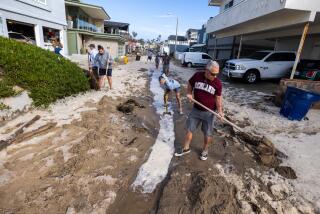 Ventura, CA - December 28: Brad Steward, right, joins neighbors with shovels as they attempt to remove sand to allow water to drain after a seawall and sand berm was breached by high surf on Bath Lane on Thursday, Dec. 28, 2023 in Ventura, CA. (Brian van der Brug / Los Angeles Times)