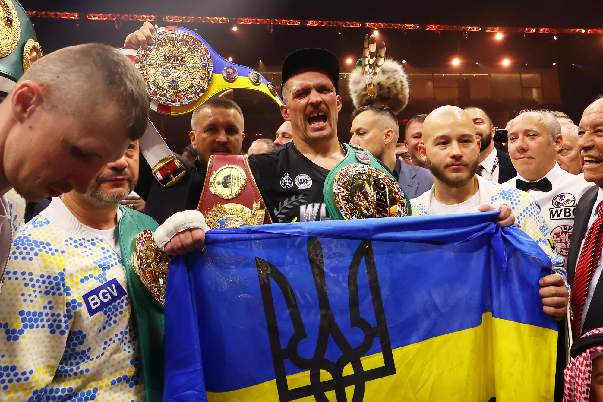 Oleksandr Usyk holds a Ukrainian flag as he celebrates with the Undisputed Heavyweight title belt.