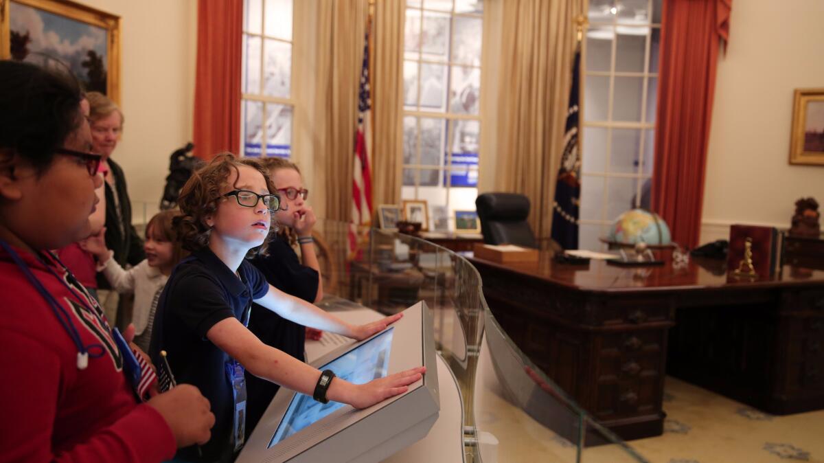 Children use a touch screen to virtually navigate a replica of the Oval Office at the Gerald R. Ford Presidential Museum.