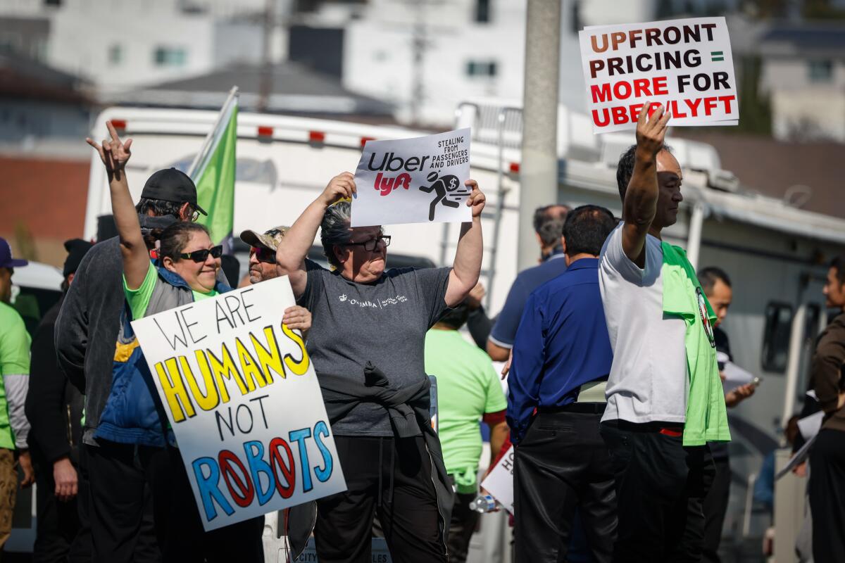 Gig drivers hold up signs at a protest