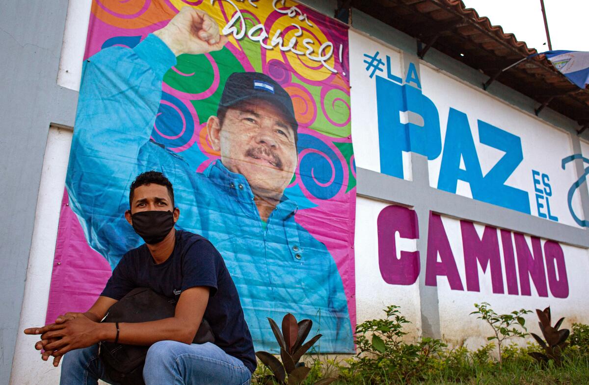 A man sits in front of a banner promoting Nicaraguan President Daniel Ortega's candidacy.