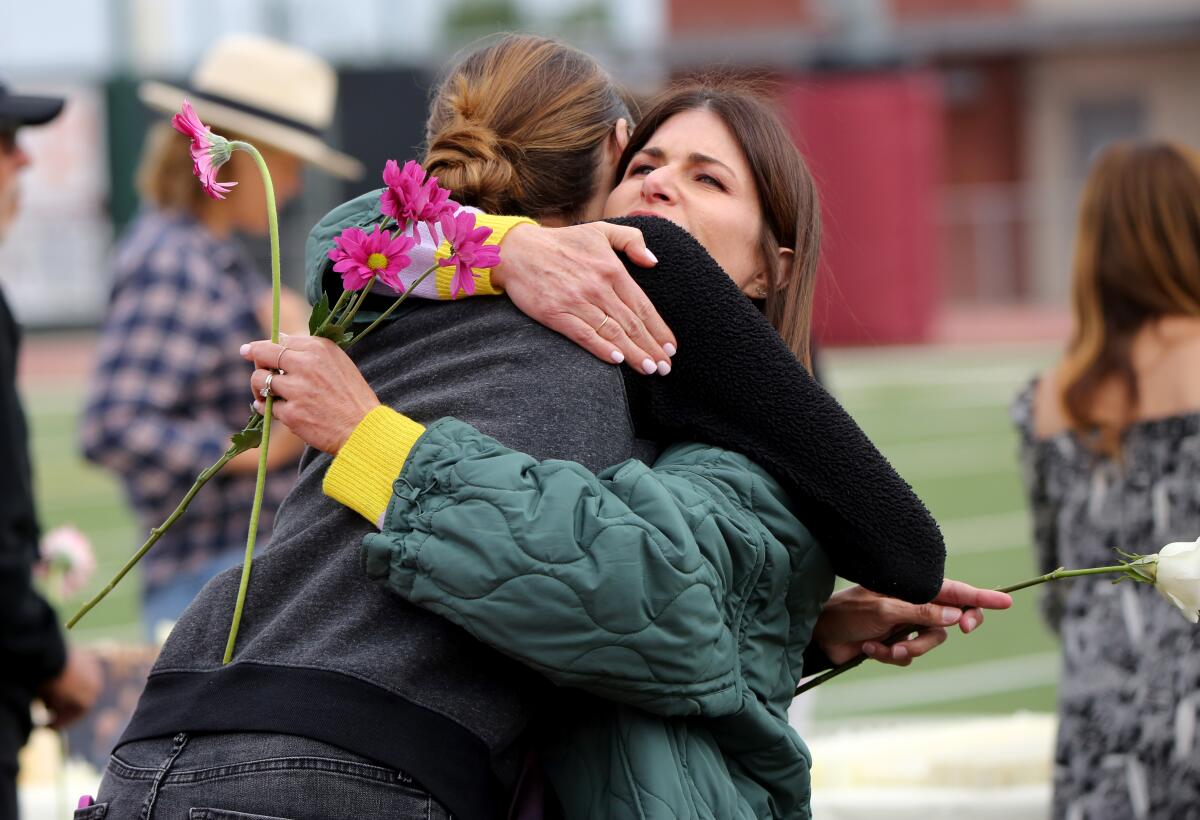 PTA mom Erin Crandall, left, and parent Michel Maniaci hug during a vigil for El Morro principal Chris Duddy.