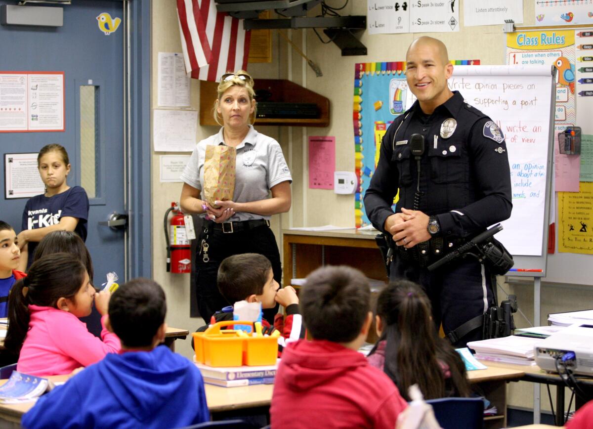 Glendale Police officer Vincent Jackson, right, and community service officer Cyndi Lindner, left, talks with Horace Mann Elementary School third graders about traffic safety at the Glendale school on Wednesday, April 1, 2015. About 30 officers and community service officers brought a truckload of Easter bags to the school and talked about traffic safety with the children.