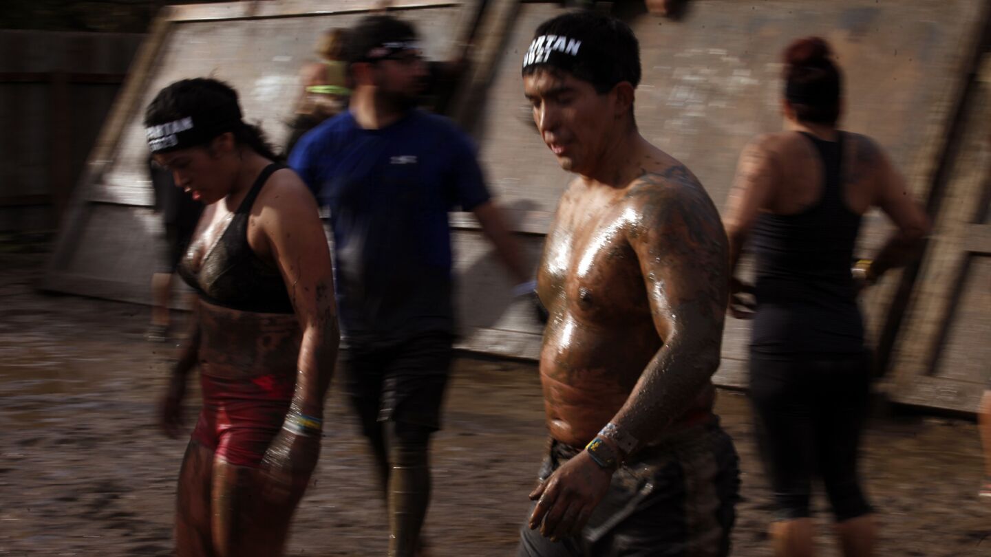 Muddy participants make their way to the "slip wall" obstacle after climbing over the "inverted wall" behind them during the Spartan Race at Calamigos Ranch in Malibu on Dec. 7, 2014.
