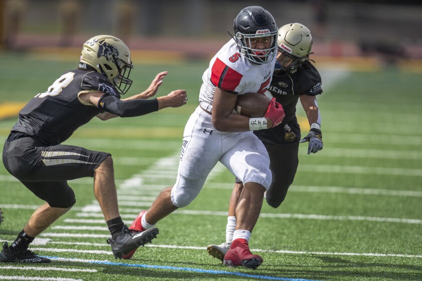 Jakob Galloway of Banning rushes against two Peninsula players.