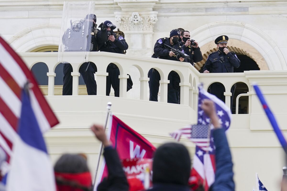 Protesters with raised fists outside the Capitol with armed officers looking on.