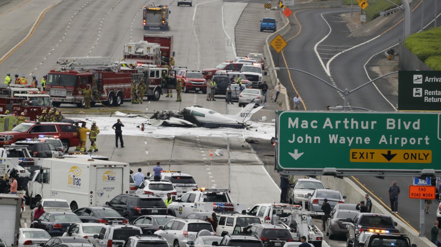 Emergency responders gather around the crash of a Cessna 310 aircraft on Interstate 405, just short of a runway at John Wayne Airport on Friday.