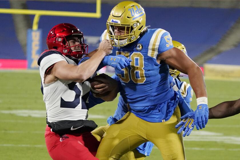 Arizona place holder Jacob Meeker-Hackett, left, is pushed out of bounds by UCLA defensive lineman Datona Jackson (58) after a botched field goal-attempt during the second half of an NCAA college football game Saturday, Nov. 28, 2020, in Pasadena, Calif. (AP Photo/Marcio Jose Sanchez)