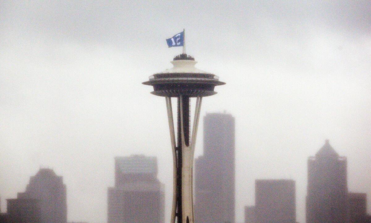A "12th Man" flag, honoring Seattle Seahawks fans, is barely visible as it flutters atop the Space Needle in the rain Wednesday, Jan. 29, 2014, in Seattle. The Seahawks play the Denver Broncos in Super Bowl XLVIII on Sunday. (AP Photo/Elaine Thompson) ** Usable by LA and DC Only **