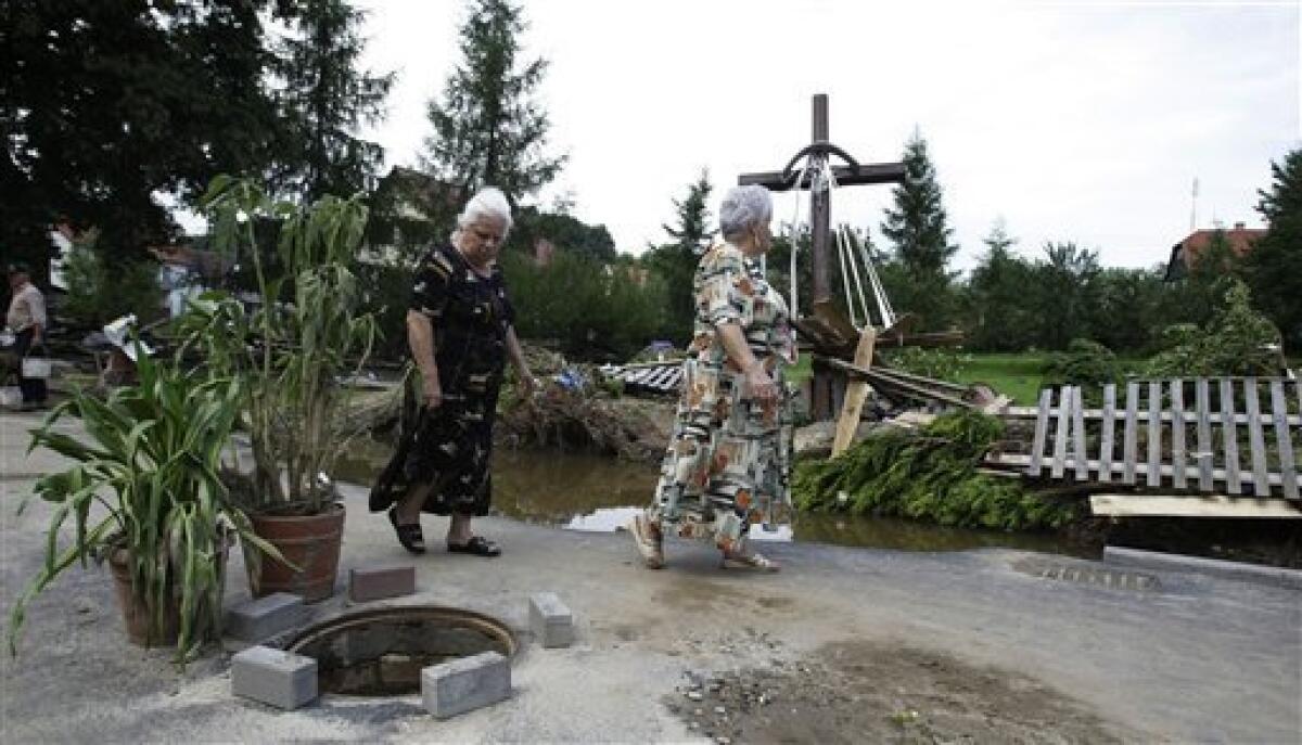 Elderly woman pass by a cross after a flash floods hit the town of Bogatynia, Poland, Sunday, Aug. 8, 2010. The flooding has struck an area near the borders of Poland, Germany and the Czech Republic. (AP Photo/Petr David Josek)