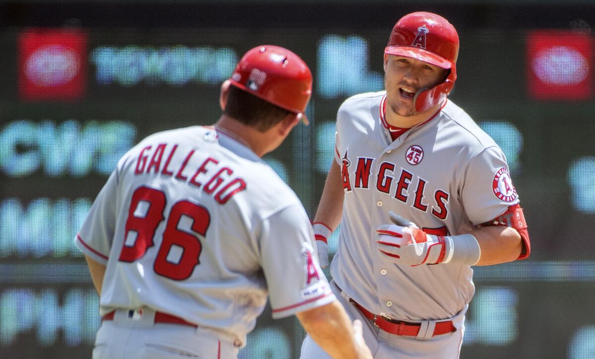 ngels slugger Mike Trout is congratulated by third base coach Mike Gallego.