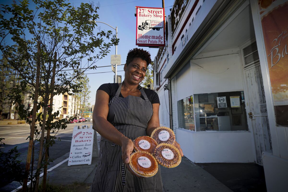 Jeanette Bolden smiles holding fresh-baked sweet potato pies in front of 27th Street Bakery Shop