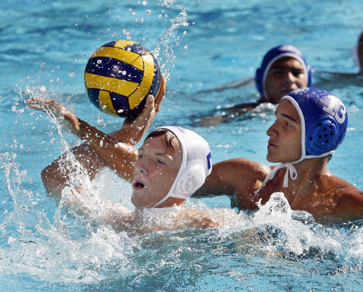 Flintridge Prep's Jamie Walker takes a shot with the defensive arm of Burbank's Andres Pulgano reaching through in the second half in a nonleague boys water polo match at Burbank High School on Monday, September 24, 2012.
