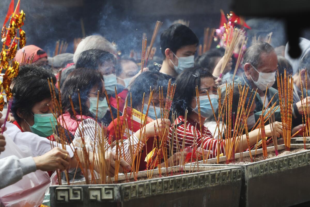 Varias personas queman varitas de incienso mientras rezan en el templo Wong Tai Sin de Hong Kong, el 25 de enero de 2020, para celebrar el inicio del Año Nuevo Lunar, que marca el arranque del Año de la Rata en el horóscopo chino. (AP Foto/Achmad Ibrahim)