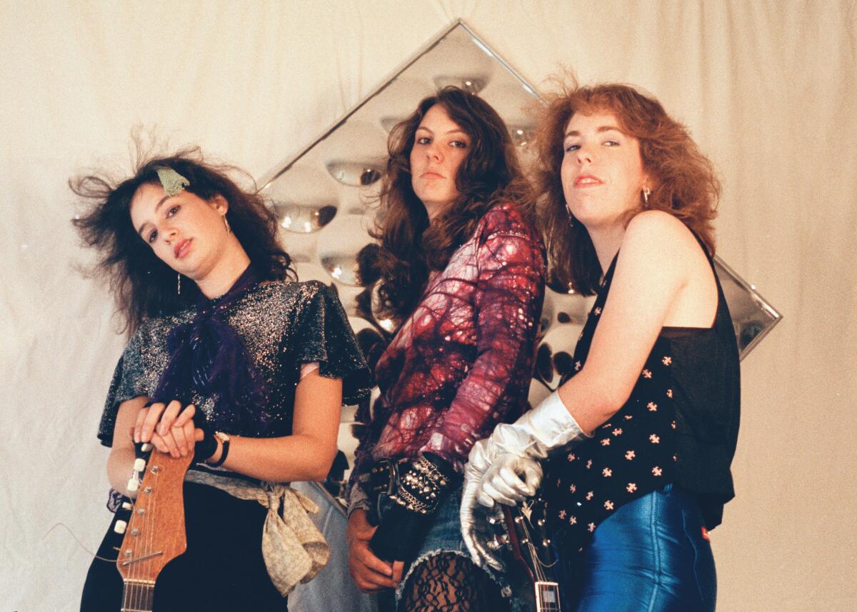Three women in 1980s clothing pose for the camera.