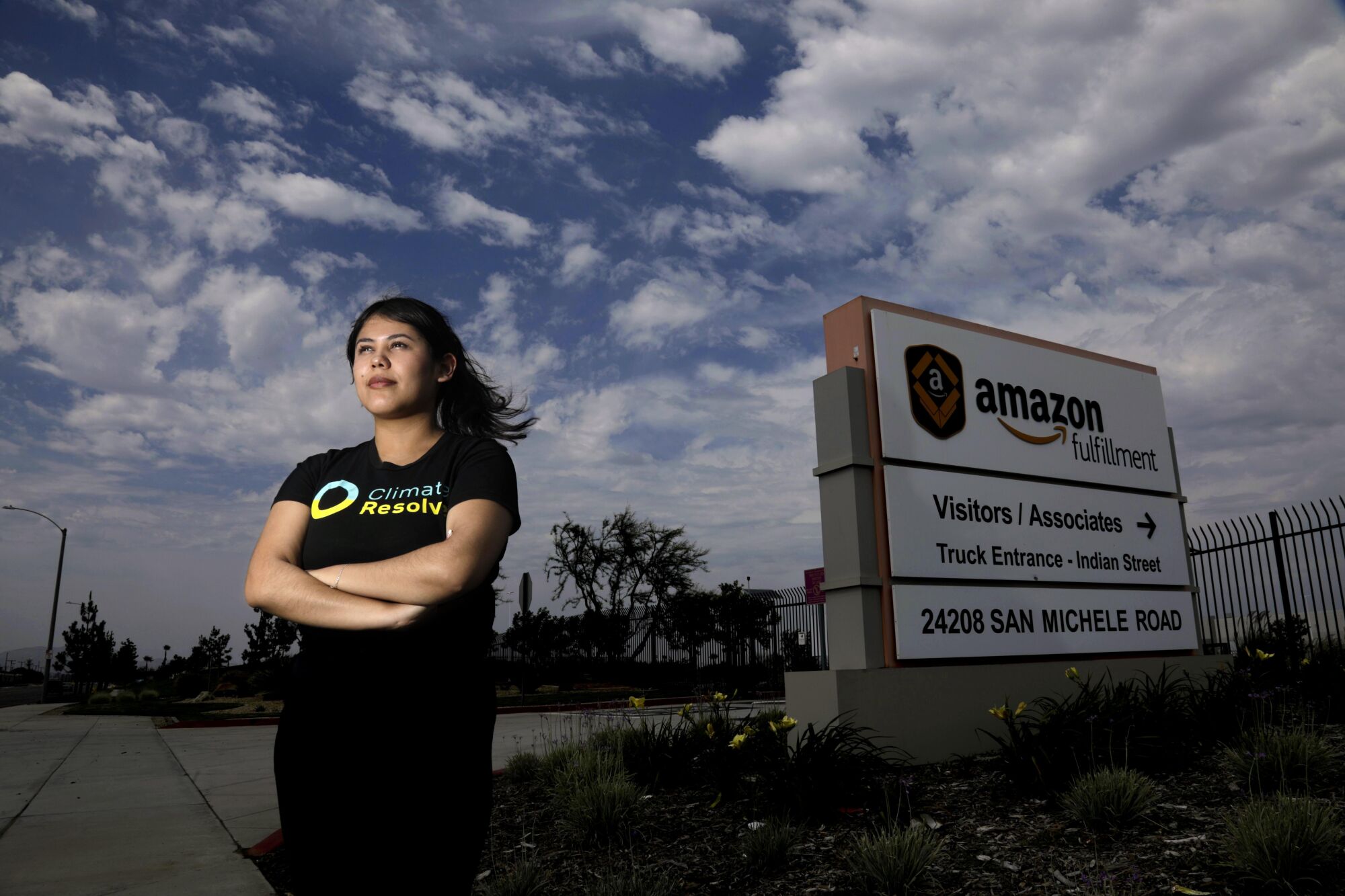 A woman stands next to a sign that says, "Amazon Fulfillment"