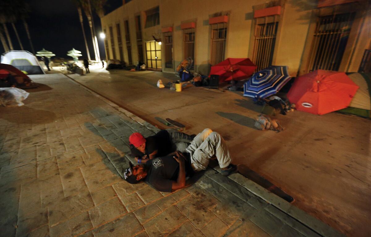 Zac Lee, 25, and Naomi Rosario, 22, who are both homeless, settle in for the night with other transients at Venice Beach on Aug. 26.