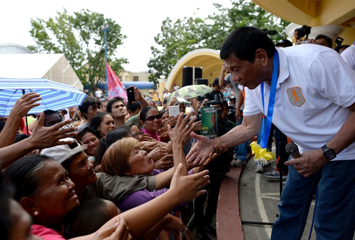 Davao City Mayor and presidential candidate Rodrigo Duterte shakes hands with supporters in Lingayen, Philippines, on March 2.