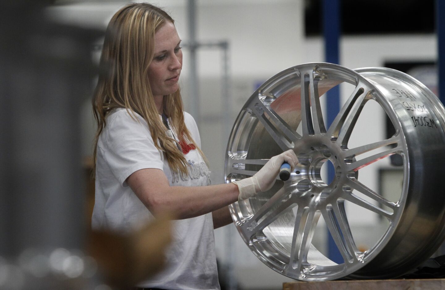 Melissa Ann Dixon carves the sharp edges from a solid aluminum wheel.