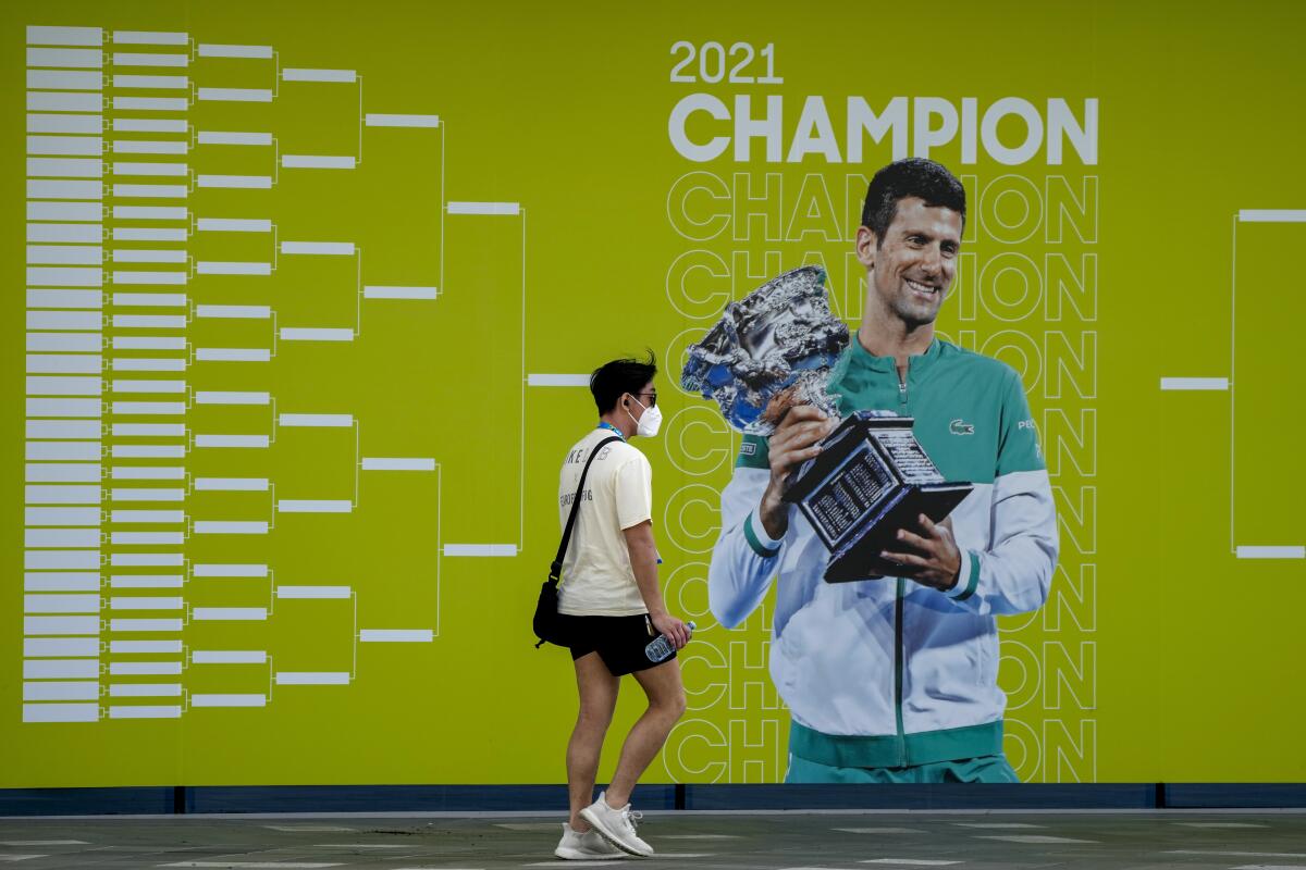 Un hombre camina junto a un anuncio del Abierto de Australia, en el que aparece Novak Djokovic.