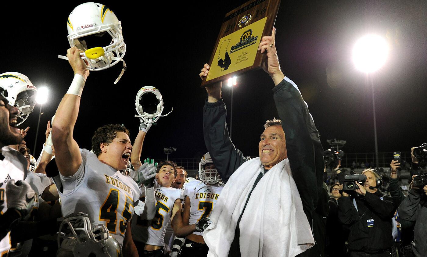 Coach Dave White holds up the championship plaque after Edison defeated La Mirada, 44-24, in the Southern Section Division 3 championship football game.