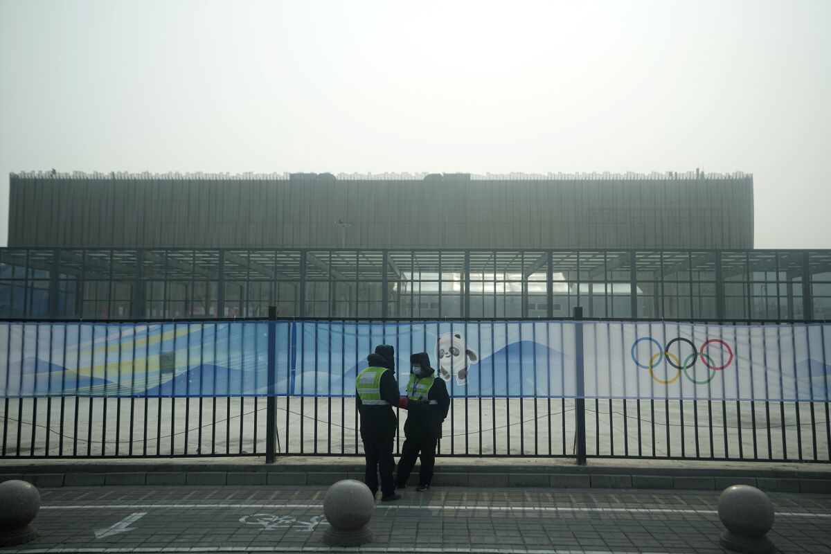 Security personnel stand on the sidewalk near Wukesong Sports Centre hockey venue ahead of the 2022 Winter Olympics, Sunday, Jan. 30, 2022, in Beijing. (AP Photo/Jeff Roberson)