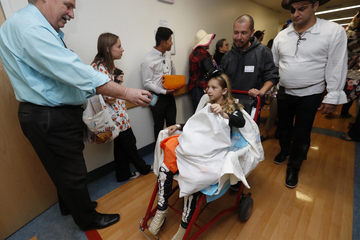 Kailyn Olivan, 10, receives treats from doctors and staff members during a daytime trick-or-treat parade in a hallway at Fountain Valley Regional Hospital & Medical Center on Thursday.