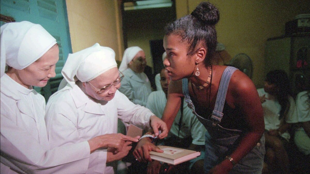 A woman shows her ID bracelet with her former name and orphanage location to Catholic nuns at an orphanage in Ho Chi Minh City on June 21, 1996. She was one of 12 orphans evacuated during the last days of the Vietnam War who returned for a tour of their homeland.