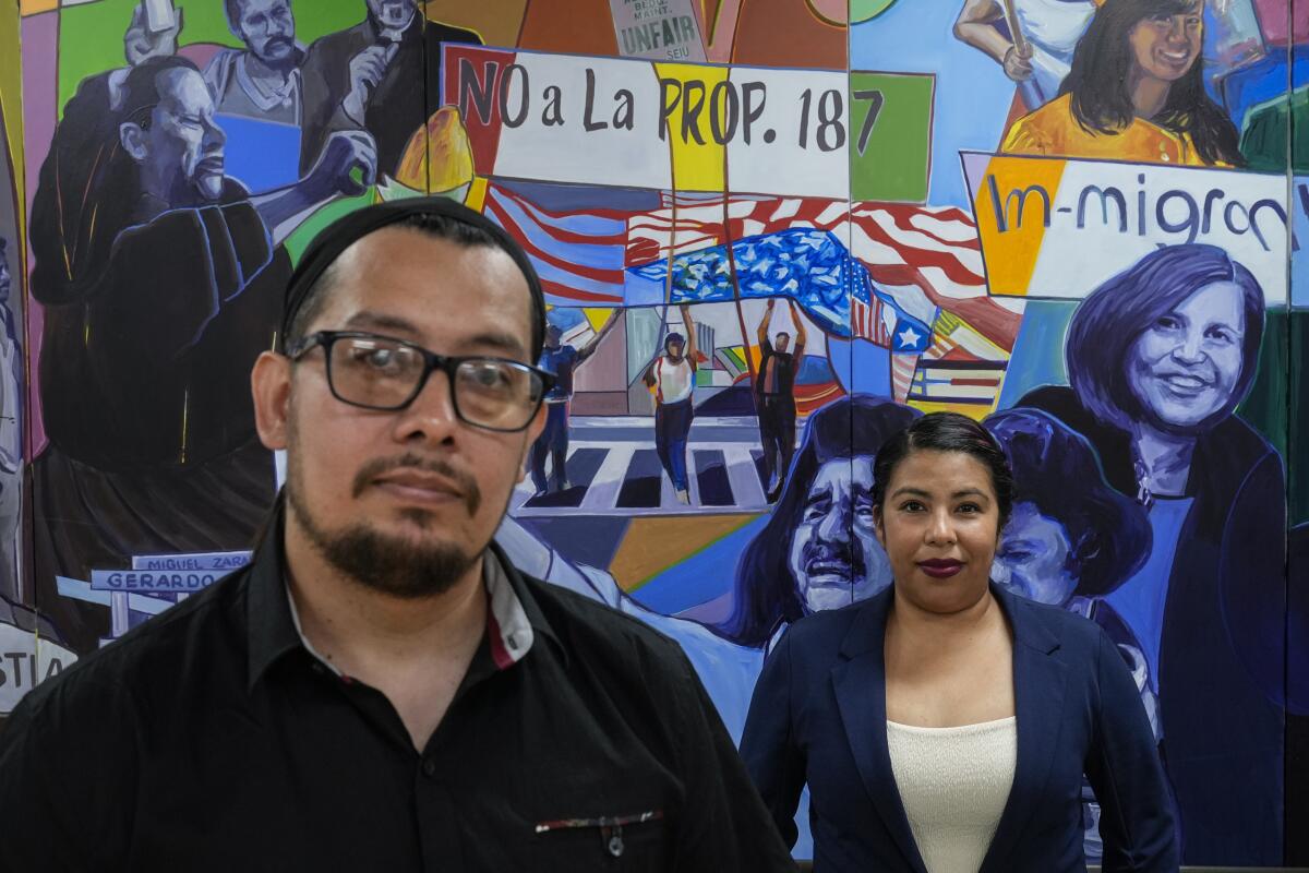 Antonio Valle, left, and his wife, Brenda Valle, standing in front of a mural