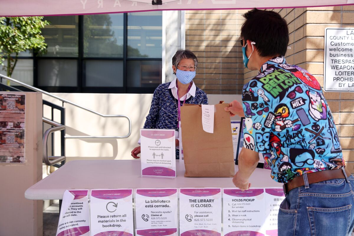 Community library manager Sue Yamamoto delivers a pickup book order to Gabe Yee at the Rosemead Library on April 9.