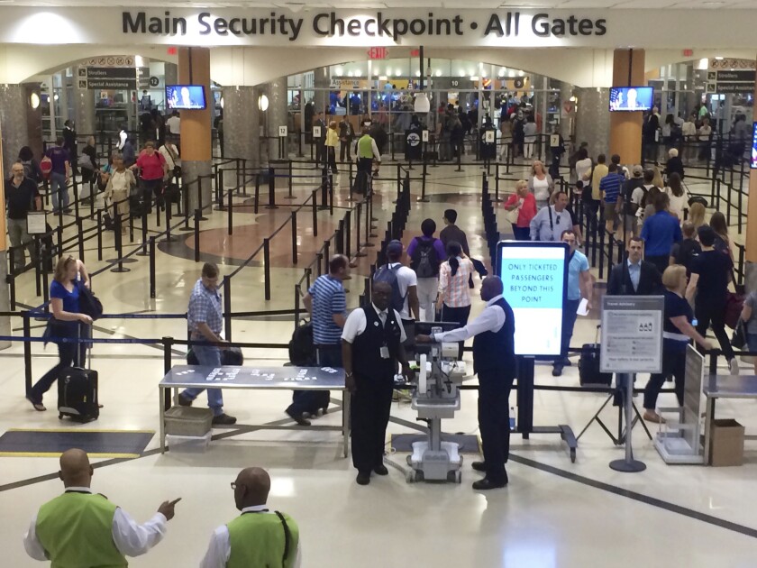 FILE - In this Friday, May 27, 2016, file photo taken from video, travelers pass through the main security gate at Hartsfield-Jackson Atlanta International Airport, in Atlanta. A man accused of accidentally firing a gun in his bag at the Atlanta airport, causing temporary chaos and prompting a temporary ground stop on flights, has turned himself in, police said Tuesday, Nov. 30, 2021. (AP Photo/Jeff Martin, File)