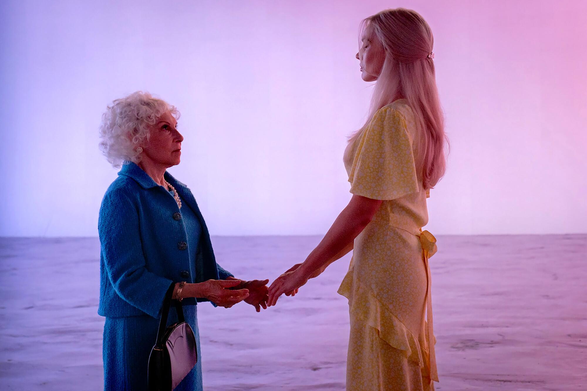 An older woman holds a young woman's hand in "Barbie."