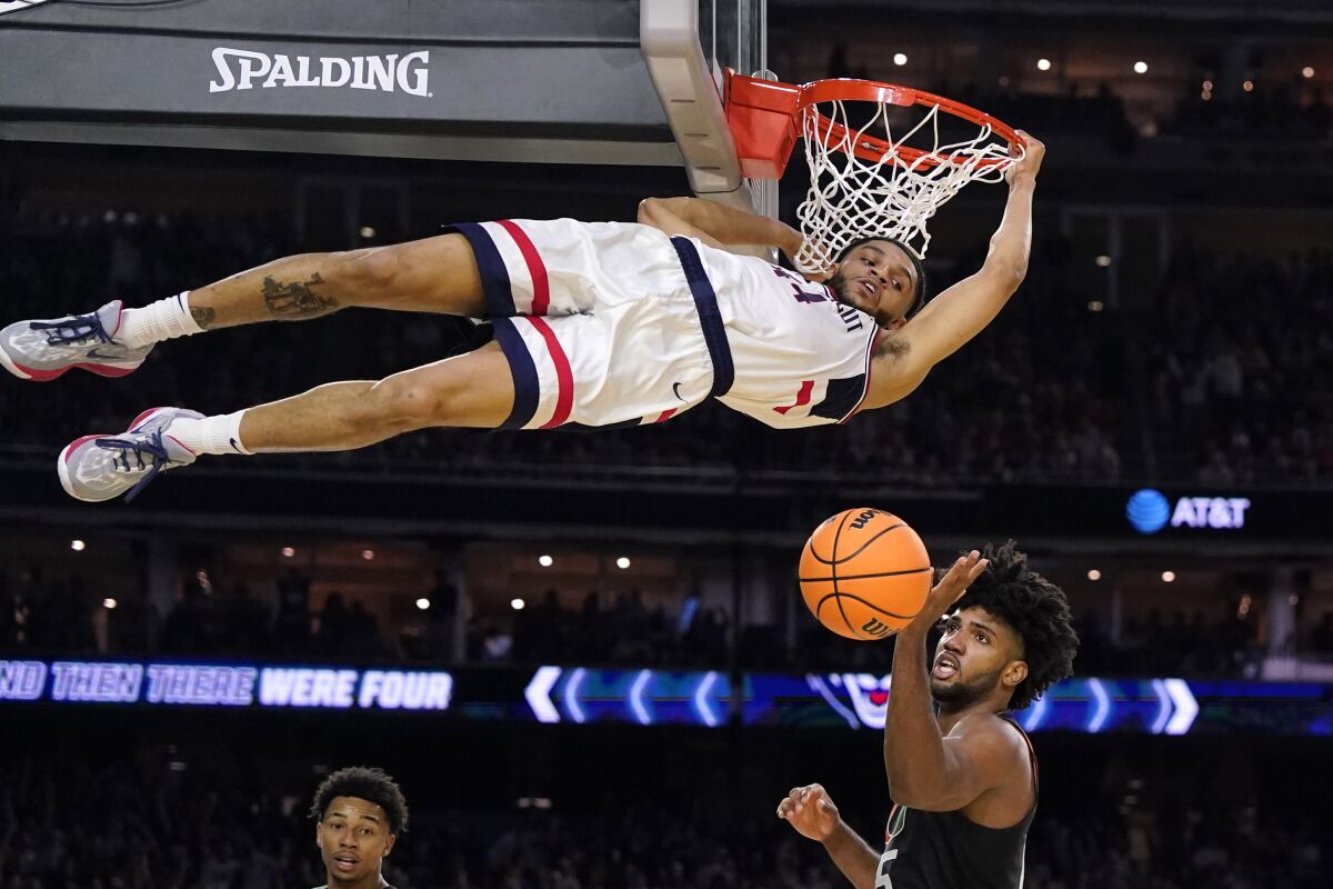 Connecticut's Andre Jackson Jr. dunks over Miami's Norchad Omier on April 1, 2023.