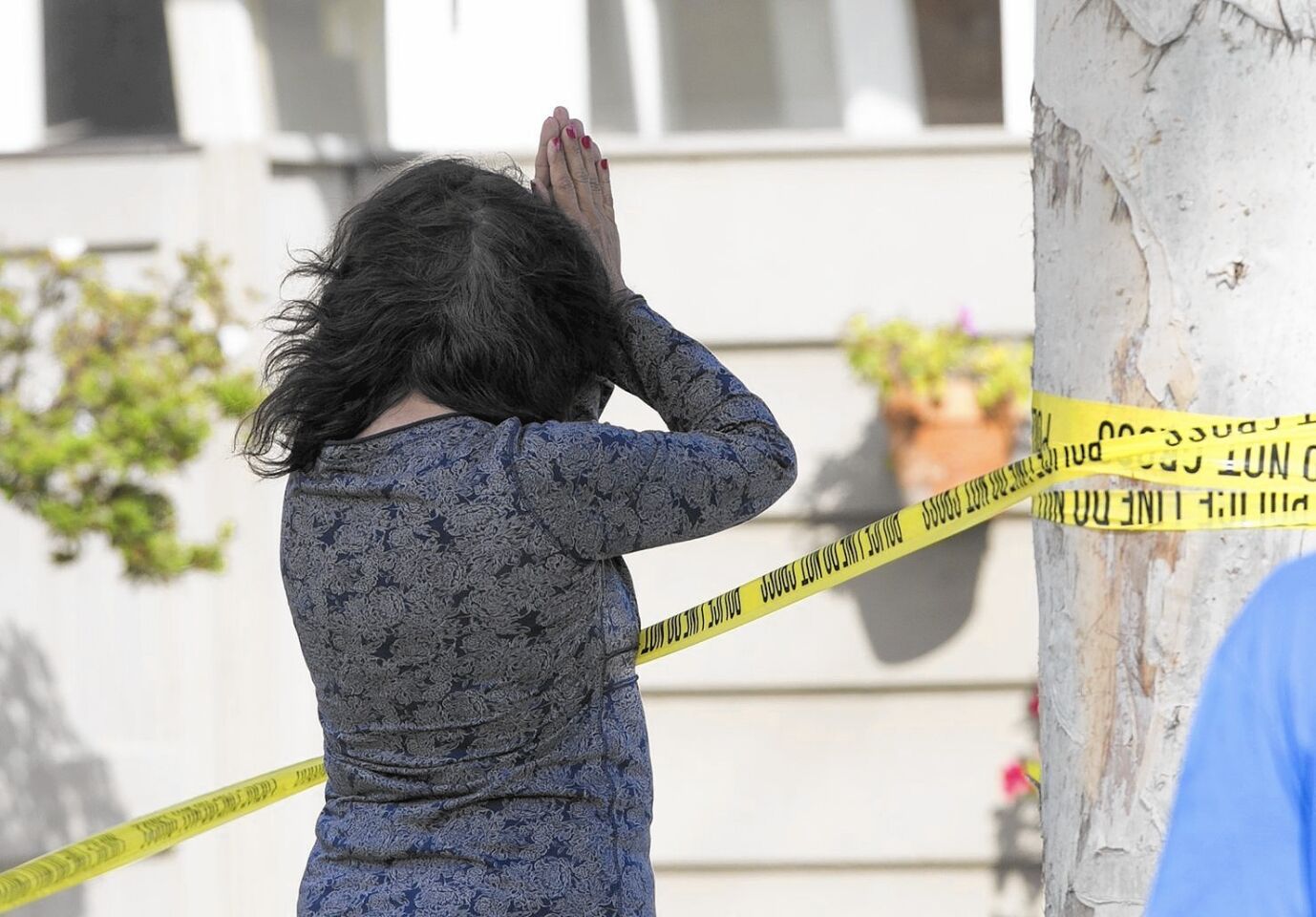 A woman prays at the corner of 15th Street and Michael Place in Newport Beach after a trash truck struck and killed an 8-year-old boy.