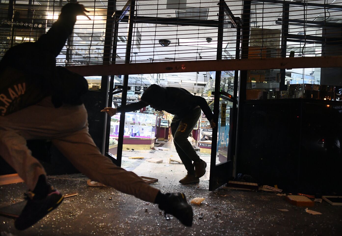 People run from a burglarized jewelry store as LAPD officers approach in downtown Los Angeles