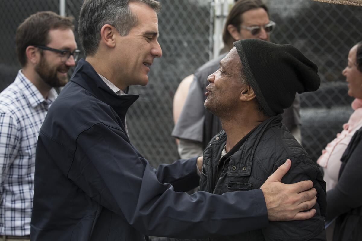 Mayor Eric Garcetti, left, embraces Anthony Hereford, 58, while meeting homeless people at the Center at Blessed Sacrament Hollywood.