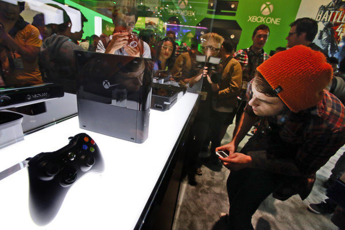A crowd gathers around the case displaying XBox One at the opening of the E3 game convention. Anticipation of the new game consoles is contributing to slowing sales.